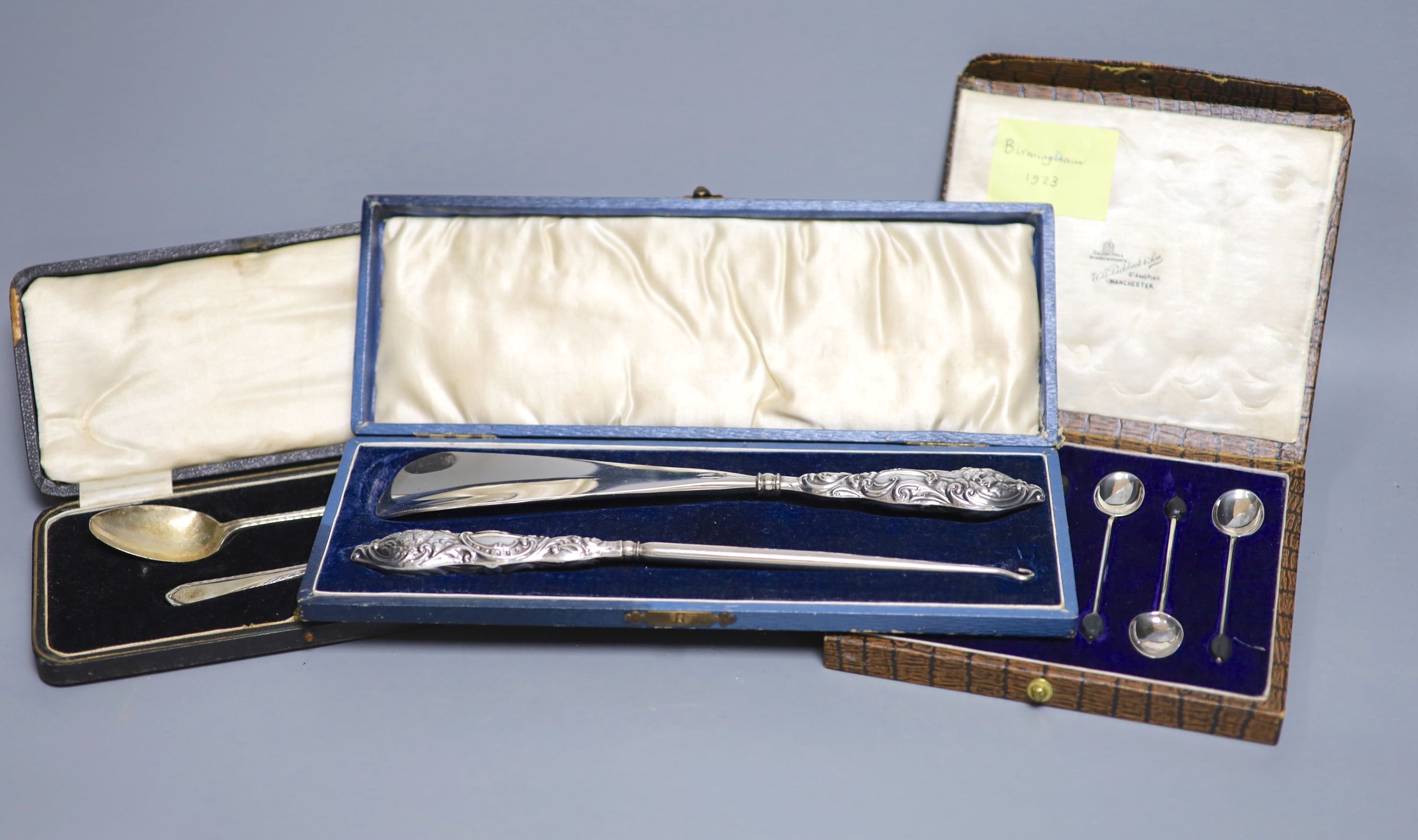 A cased set of six silver bean end coffee spoons, a cased silver spoon and pusher and a cased silver handled shoe horn and button hook.